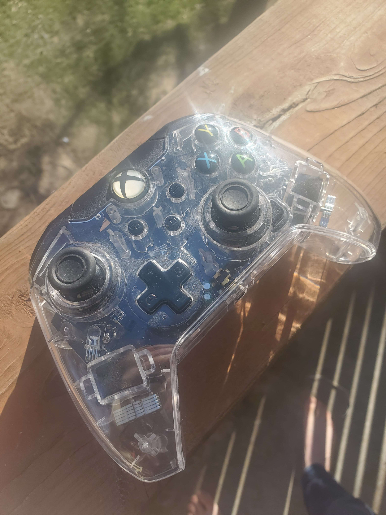 alt-text: pictures of a clear plastic xbox controller. It's shown on my porch-deck with the sunlight streaming in, and there seems to be a sparkle in the sheen of the transparent covering. Perhaps it's reflections from the various circuits and gizmos that are apparent in it's central form, or perhaps it's simply a trick of the light. Upon being placed in shadow, the inner-workings do not appear to sparkle in that same way, so perhaps the beauty is derived from the slivers of the sun that danced across the space between earth and our star. In any case, the entire controller is quite dusty, as if it had been hidden in a paper grocery bag that was shoved in the back of the closet of a boy who doesn't think to clean often. Frankly it's just not worth the trouble, and if he made any messes he would pick them up... but why bother with the little stuff? it's good enough, this is how he lives, so why would we be inconsiderate of his lifestyle? the final picture is of the audio jack.