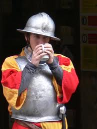 picture of a guard or squire wearing a breastplate and kettle helm and drinking tea